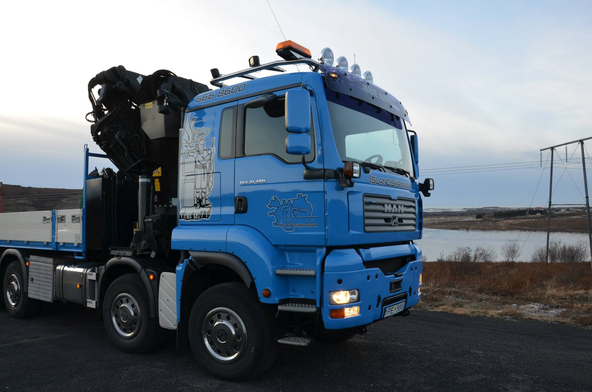 Kranabíll Íslandskrana, blá 8x8 vörubifreið með krana, á verkstað